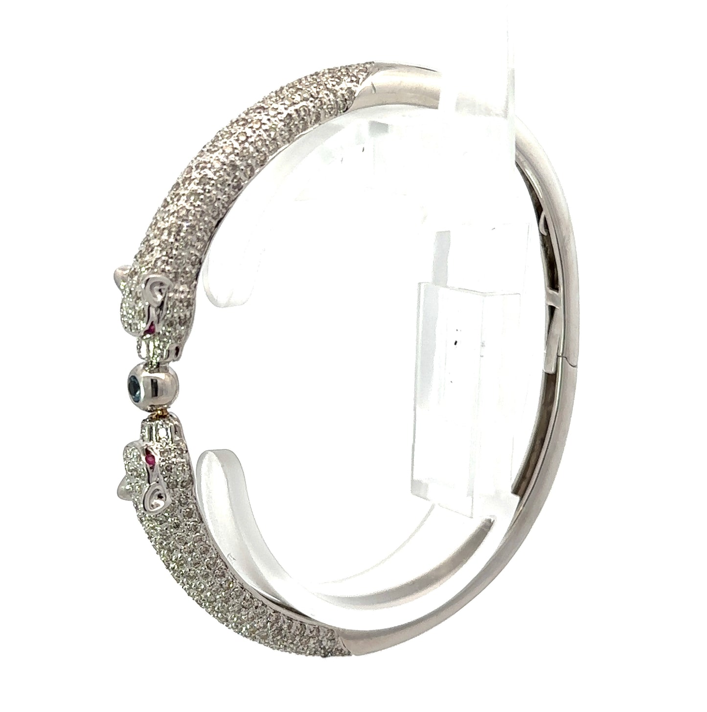 Diagonal view of white gold bangle with 2 diamond panthers and red gemstones for eyes.