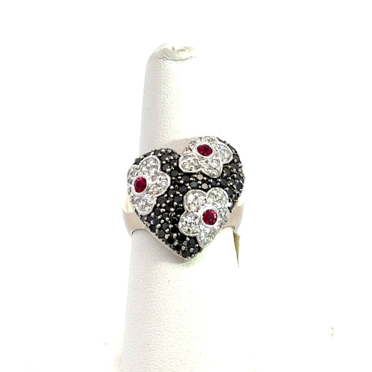 front of heart ring with flower detailing and black and white small round diamonds and 3 ruby gemstones