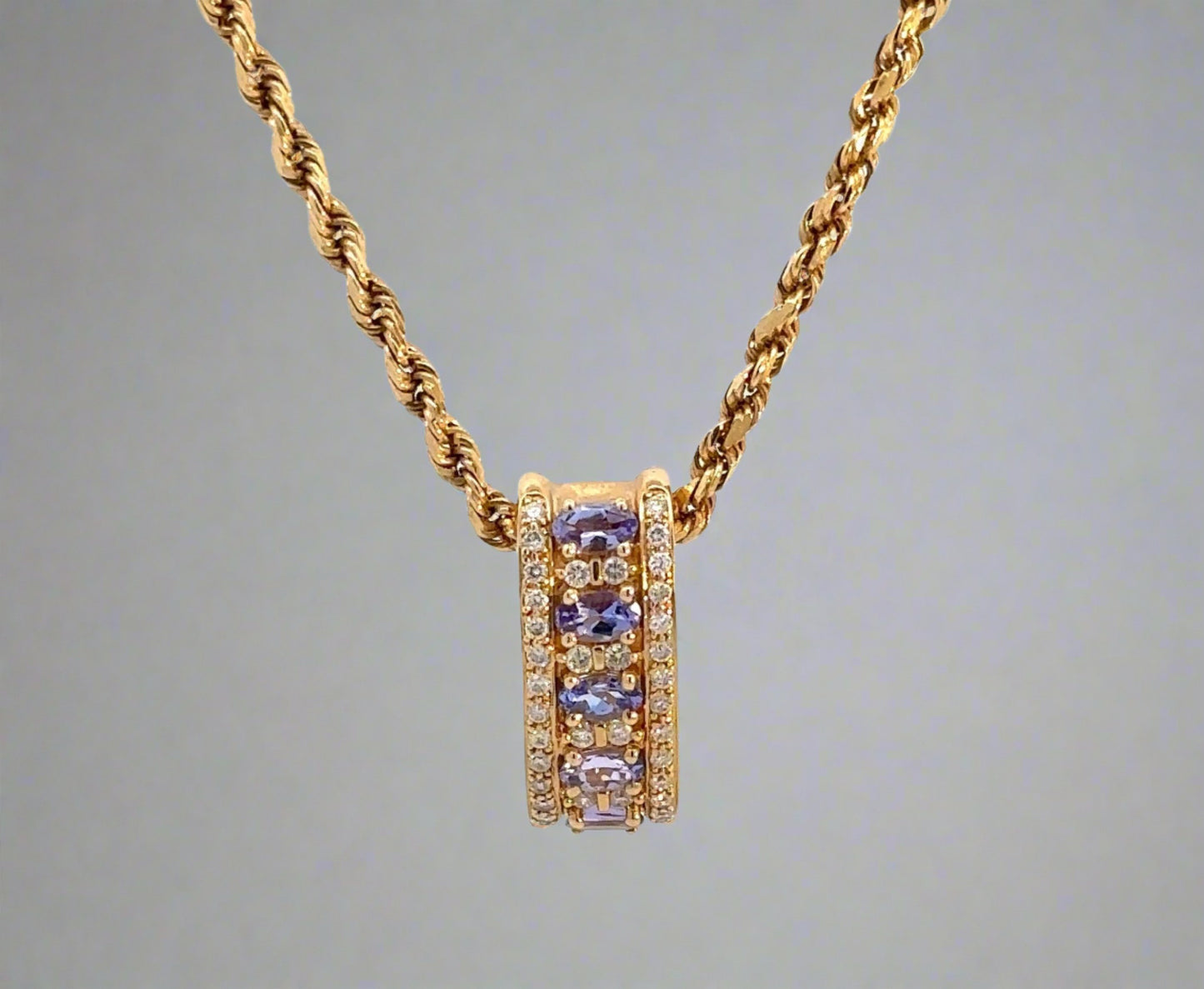 front of yellow gold rope chain and yellow gold diamond and gemstone pendant