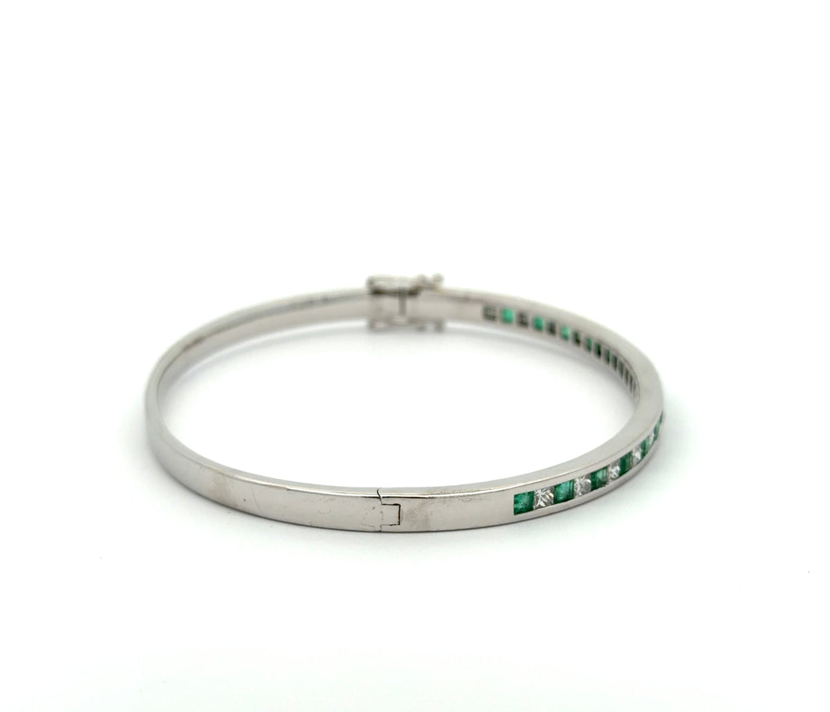 Side of white gold princess-cut diamond and emerald bangle bracelet on white background
