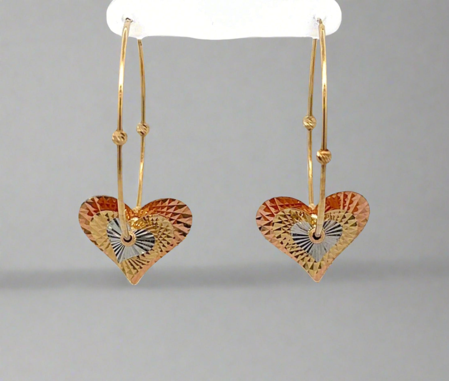 Front of yellow gold hoops with rose gold, yellow gold, and white gold heart