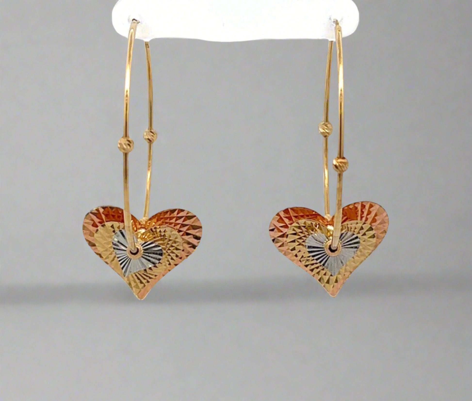 Front of yellow gold hoops with rose gold, yellow gold, and white gold heart