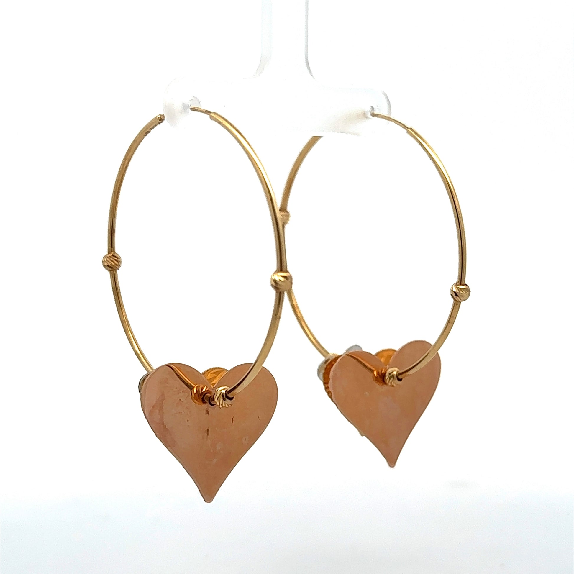 Diagonal back view of yellow gold hoops with rose gold heart. Rose gold heart has marks on the back