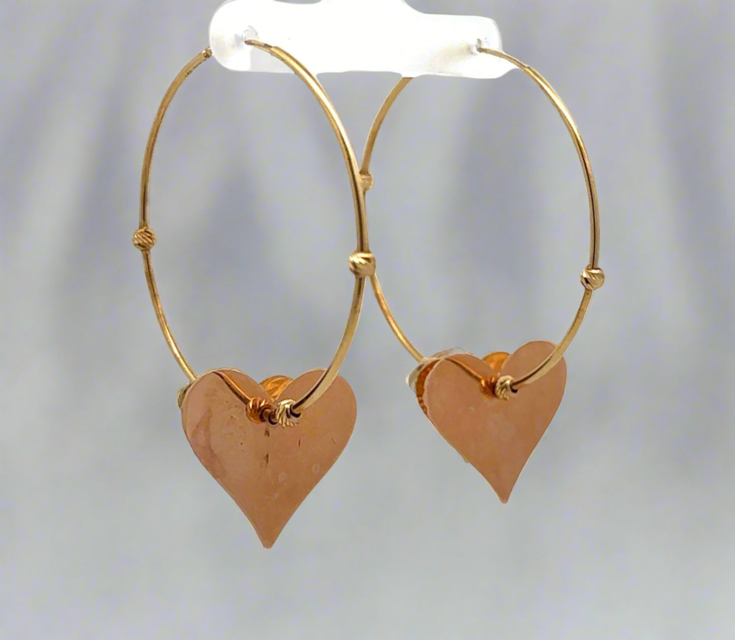 Diagonal back view of yellow gold hoops with rose gold heart. Rose gold heart has marks on the back