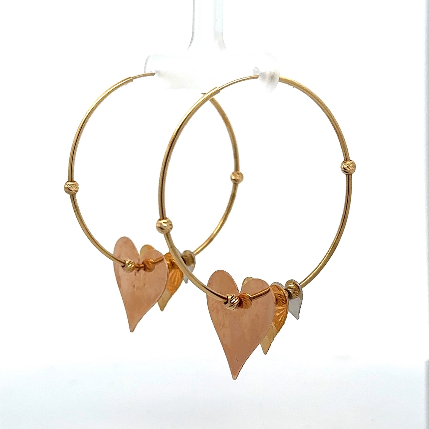 Diagonal view of yellow gold hoops with hanging hearts