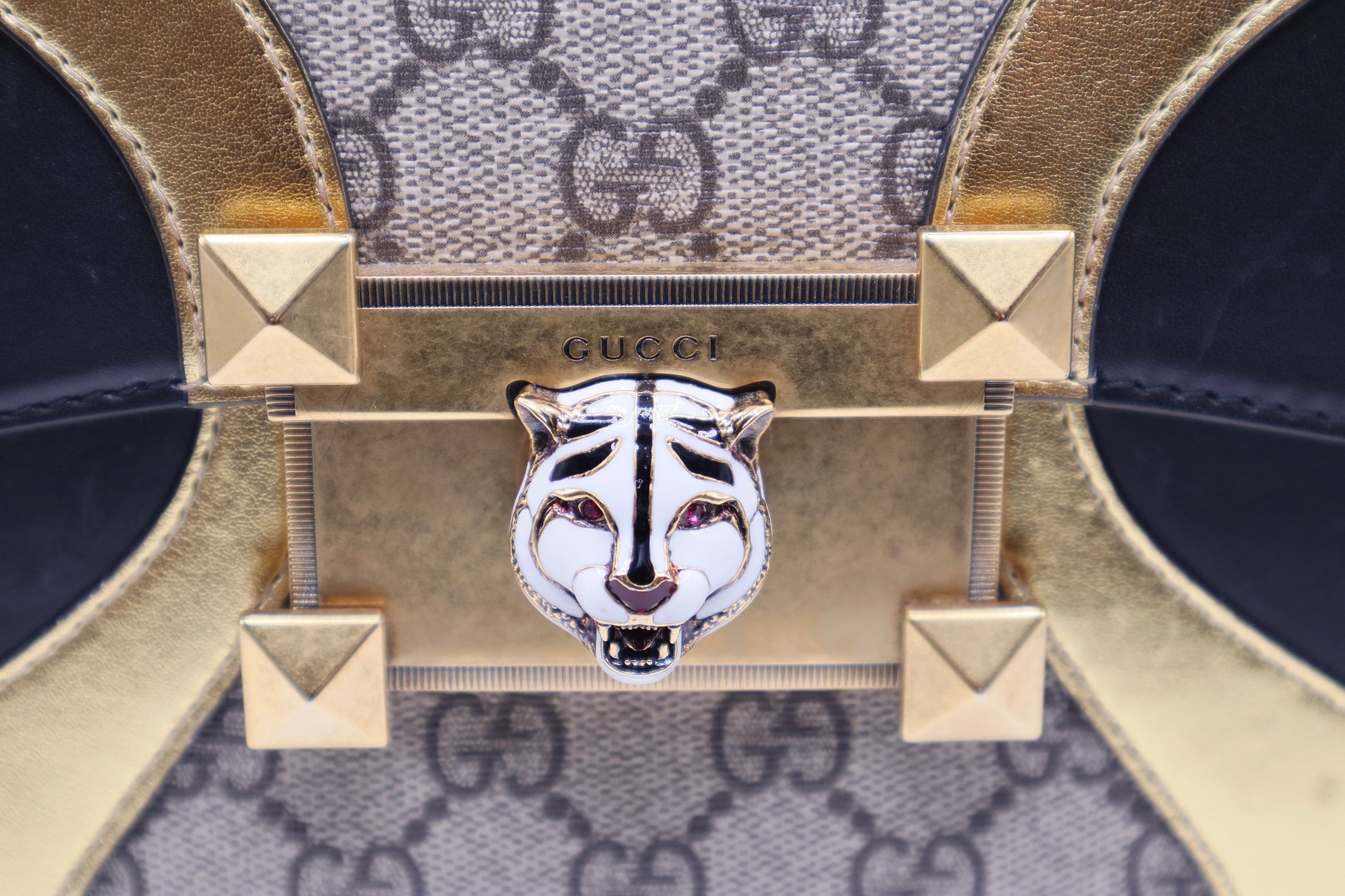 close up of white tiger emblem on gold s-lock closure with scratches