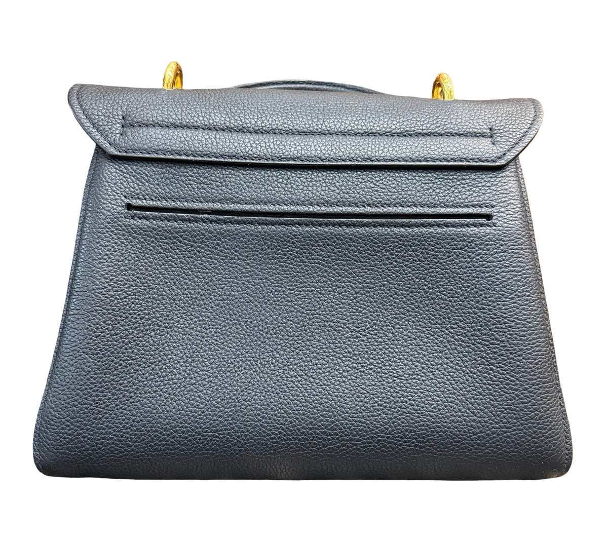 Back of a black pebbled leather handbag with gold-tone hardware, against a plain white background.