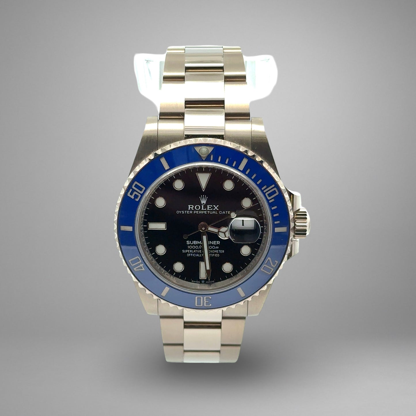Rolex watch with blue bezel and silver case on gray background