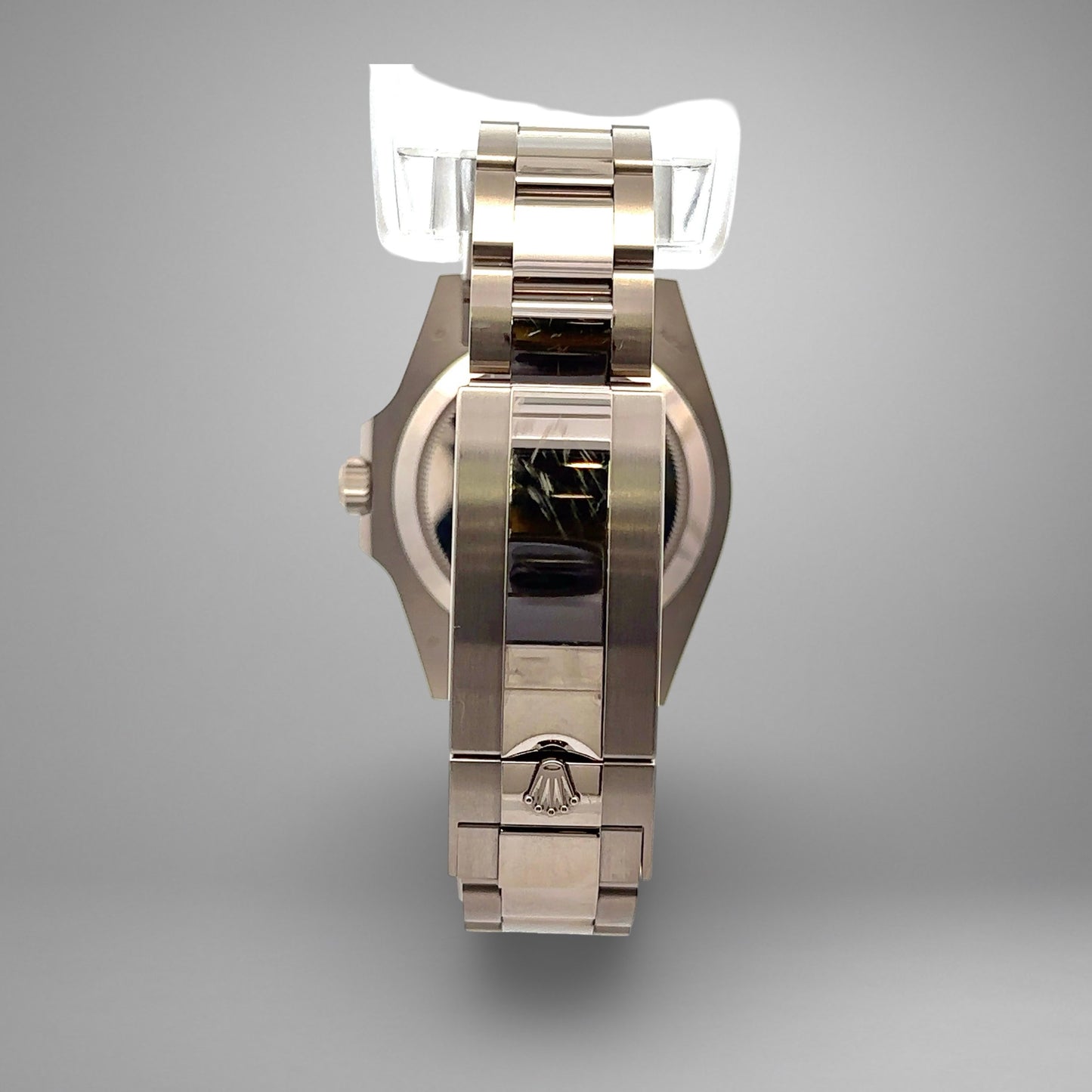 Silver watch with a reflective surface on a gray background. Scratches on band