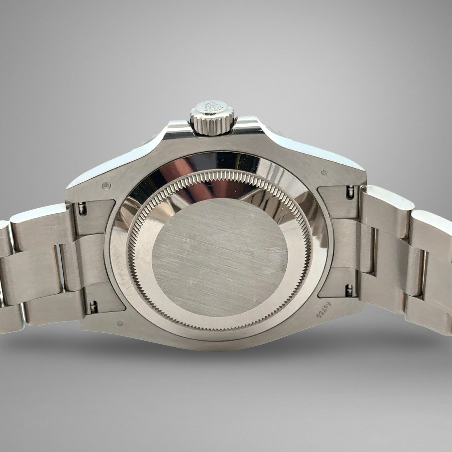 Close-up of a silver watch with a metallic band on a gray background