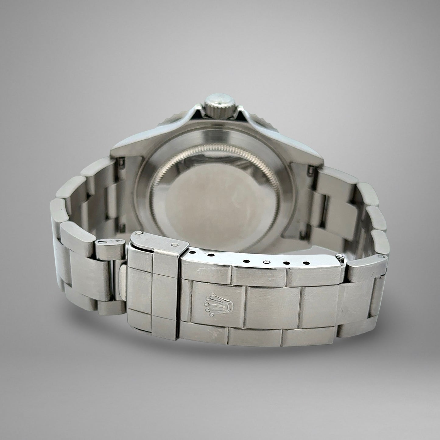 Close-up of a silver watch with a brand logo on a gray background