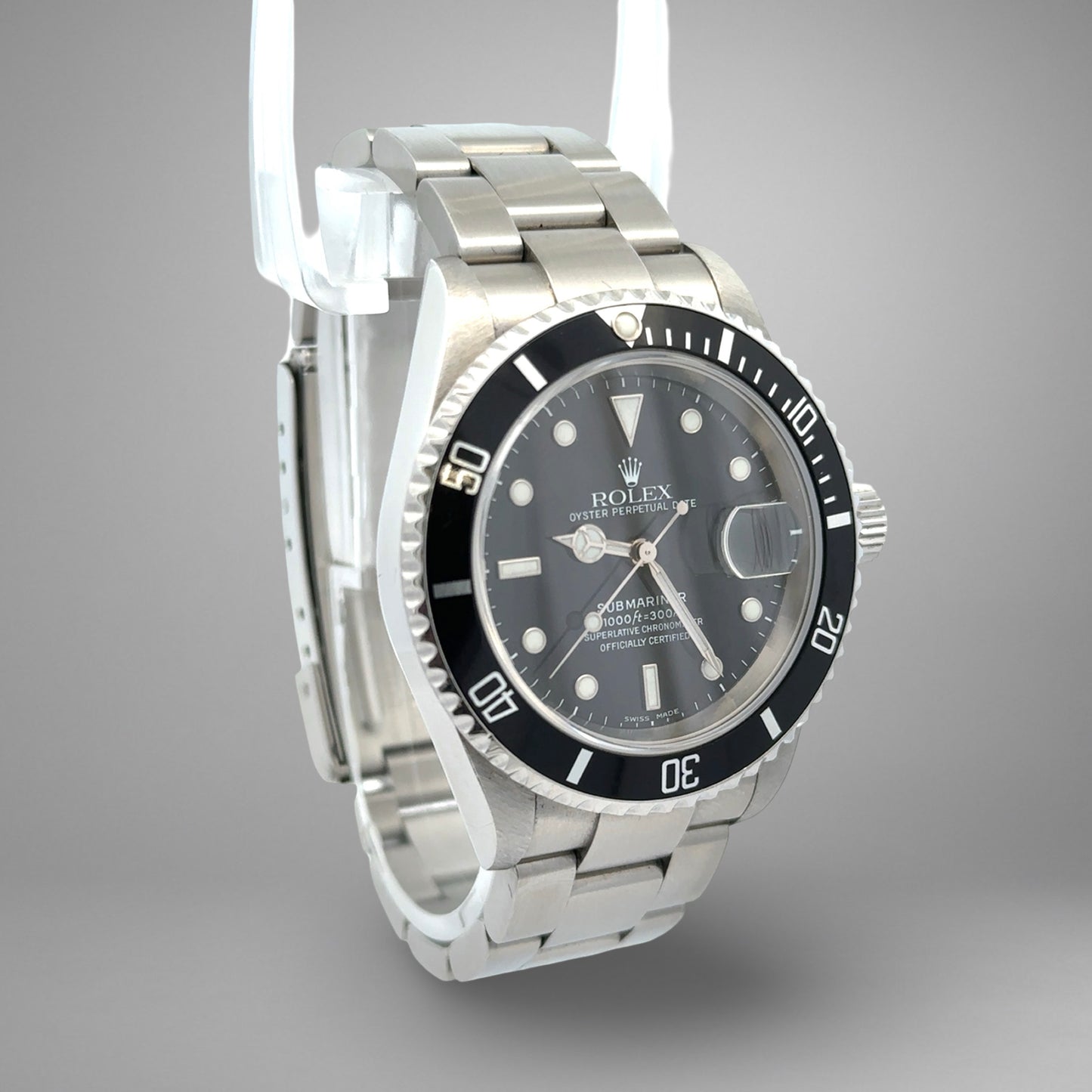 Rolex watch with black dial and silver metal strap on a gray background