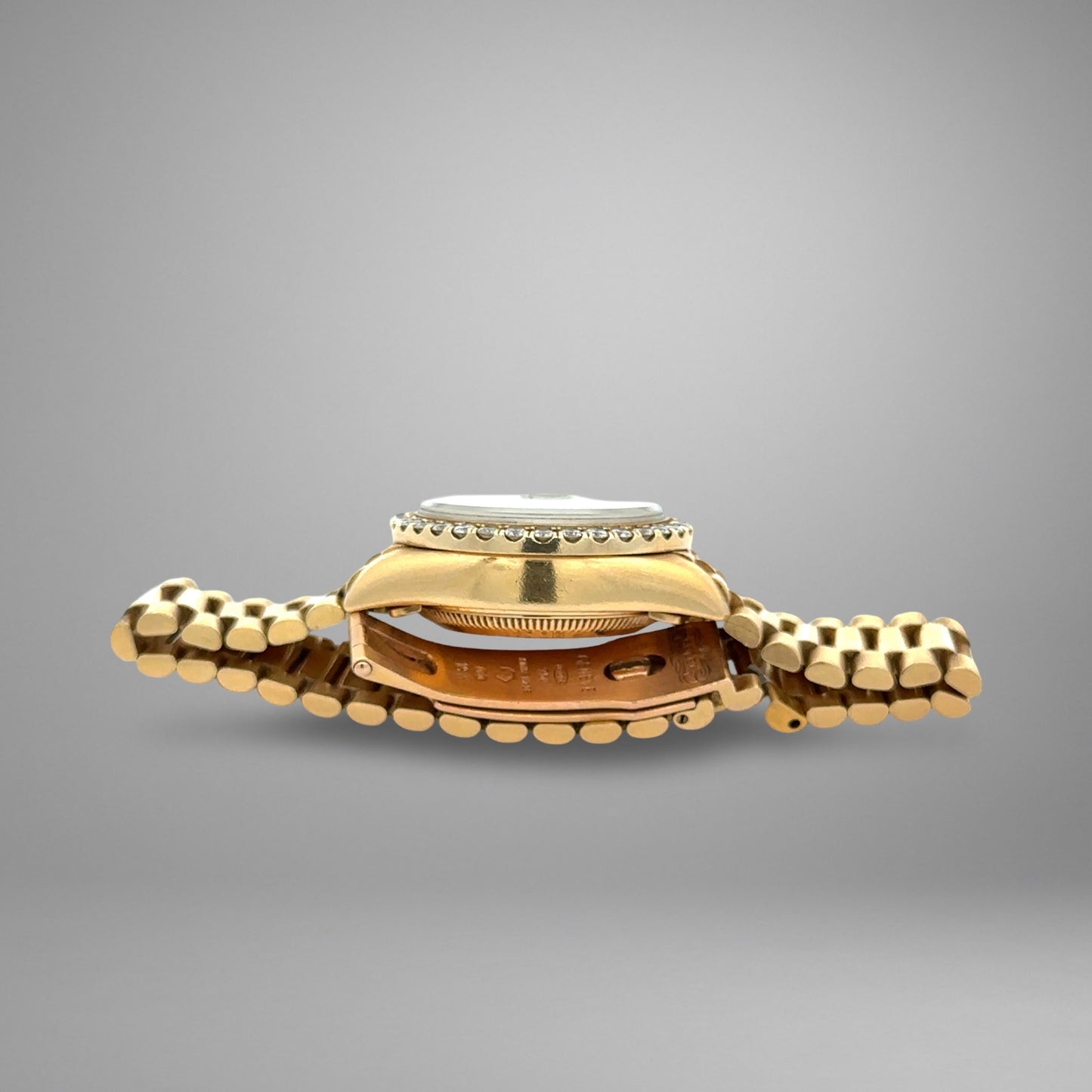 Gold watch with a textured band on a gray background