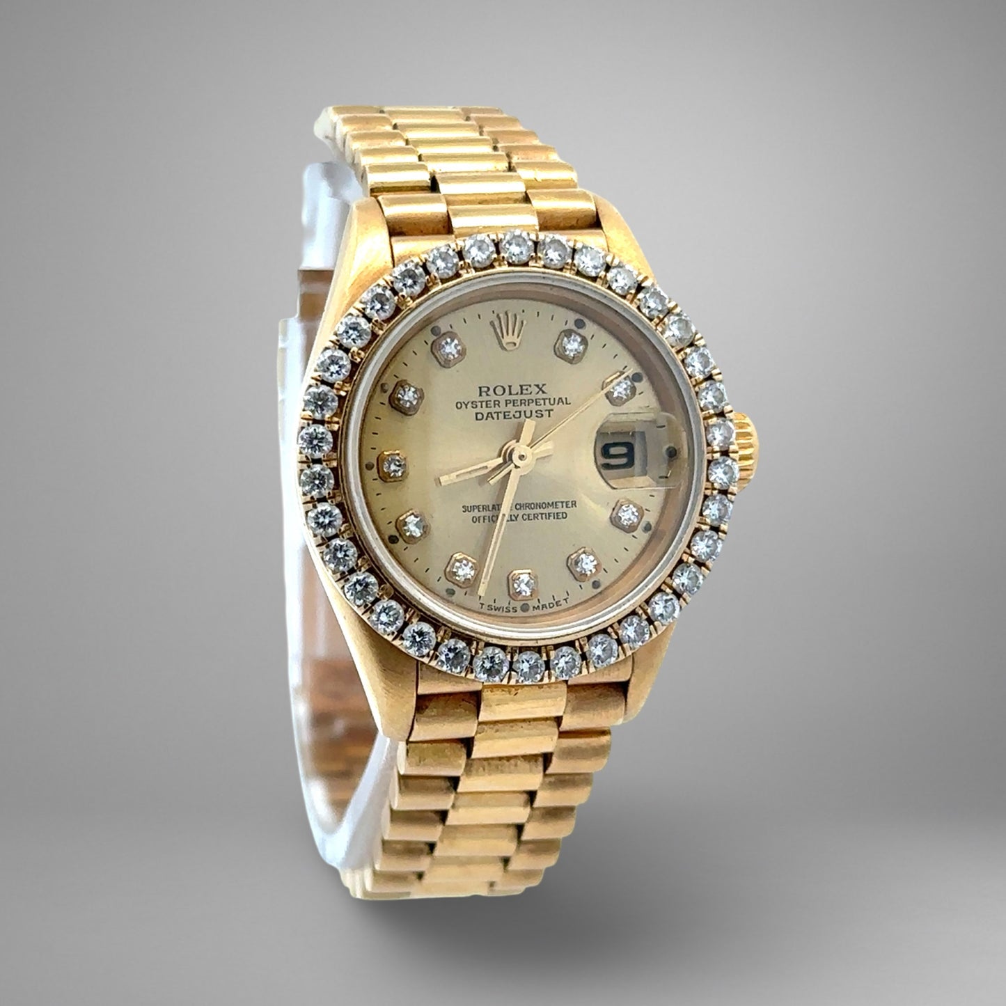 Gold watch with diamond-studded bezel on a gray background