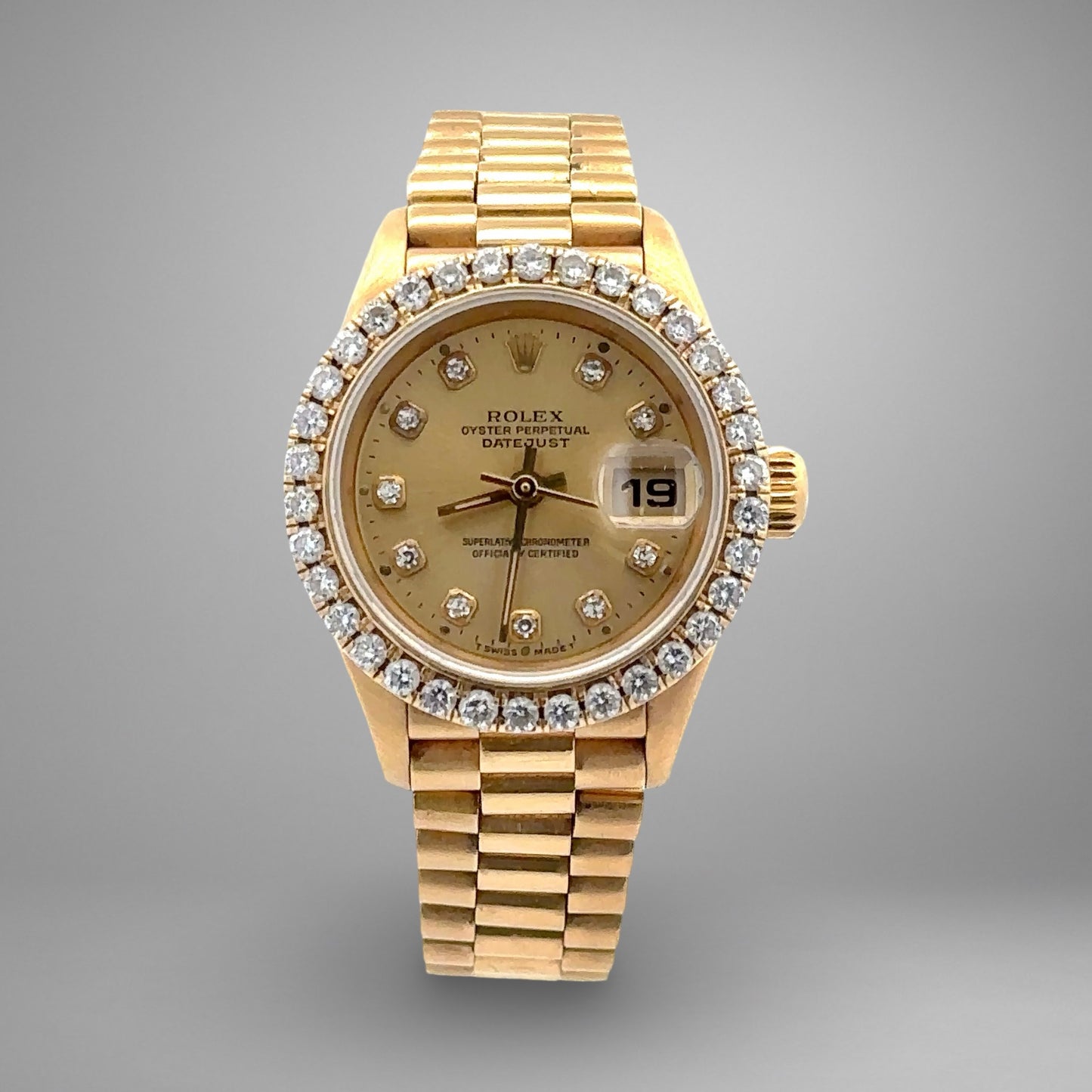 Gold watch with diamond bezel on a gray background