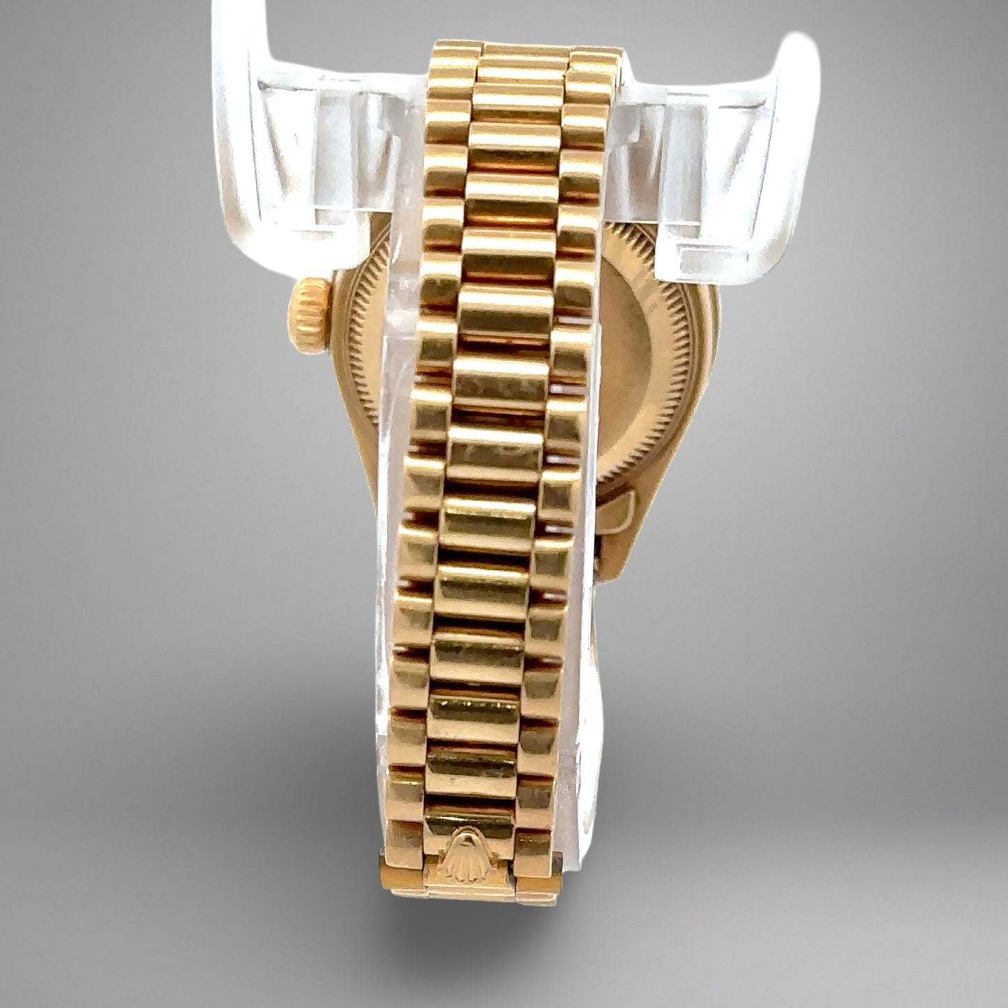 Gold watch with a clear plastic stand on a gray background