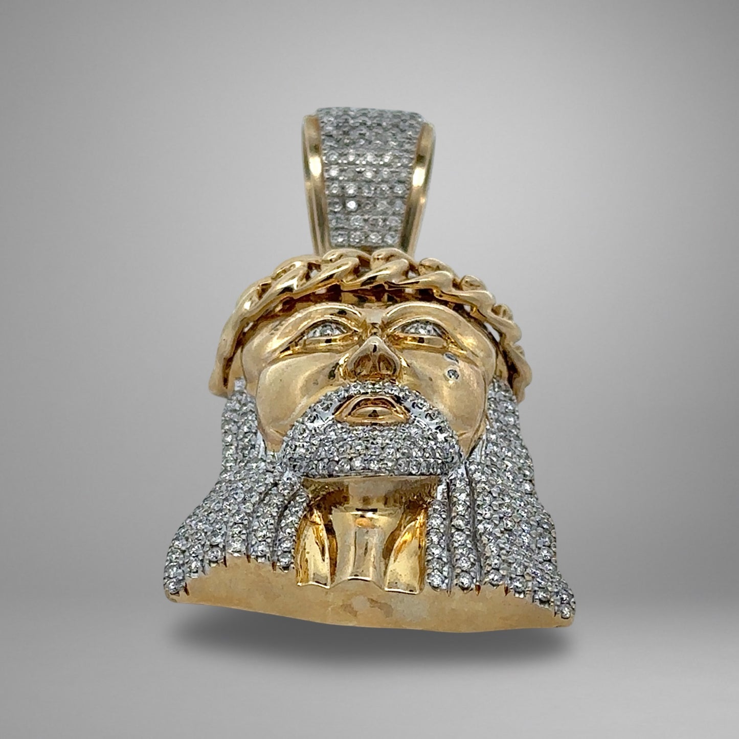 Gold pendant with diamond accents on a gray background