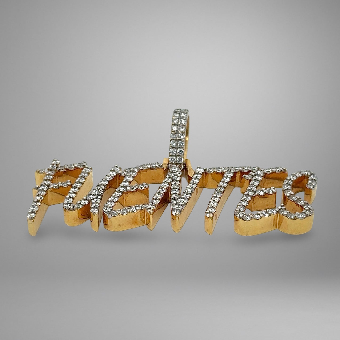 Gold and diamond-encrusted word pendant "FUENTES" on a gray background