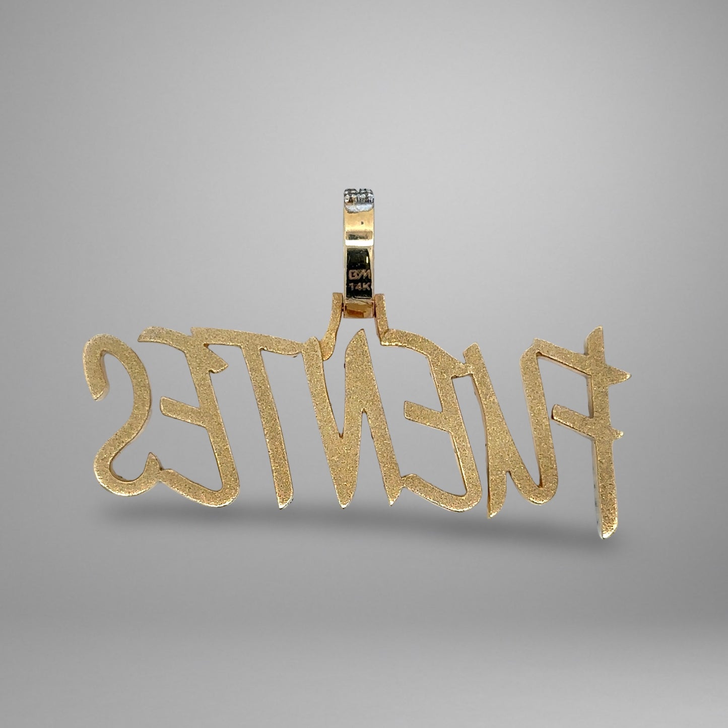 Gold pendant with 'FUENTES' engraved on a gray background