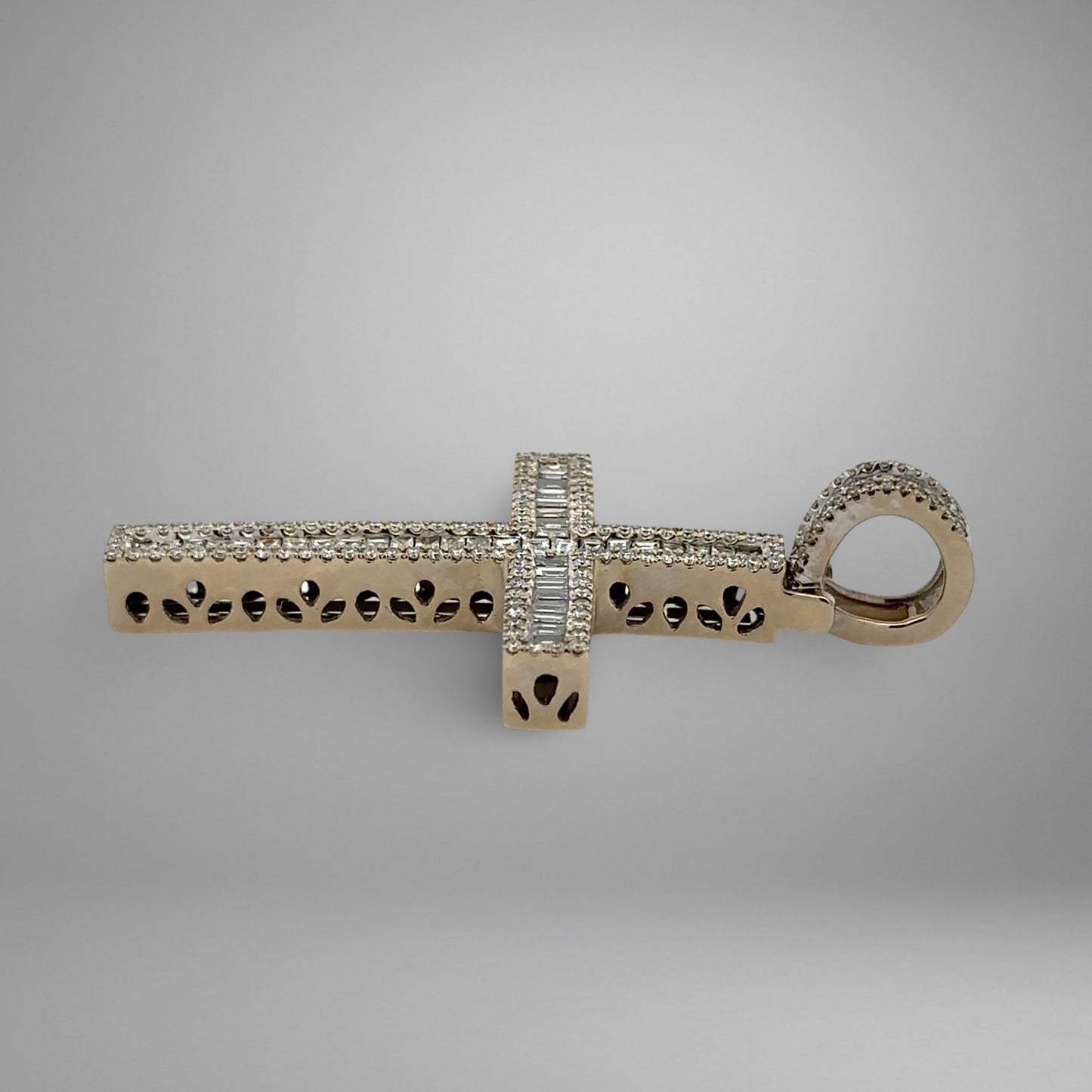 Silver cross pendant with intricate design on a gray background