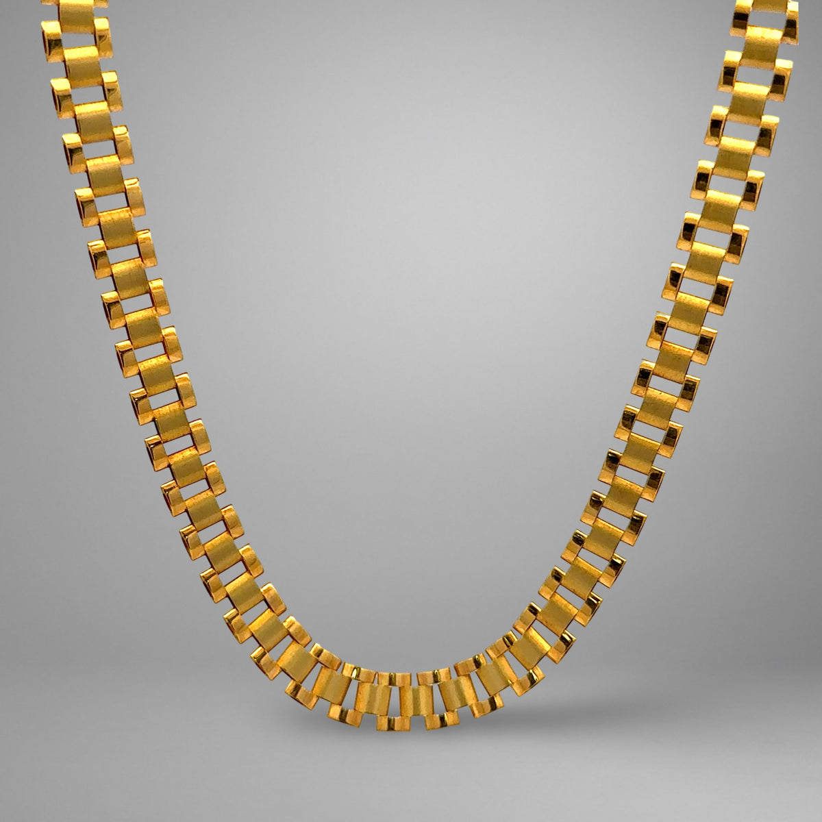 Gold chain necklace on a gray background