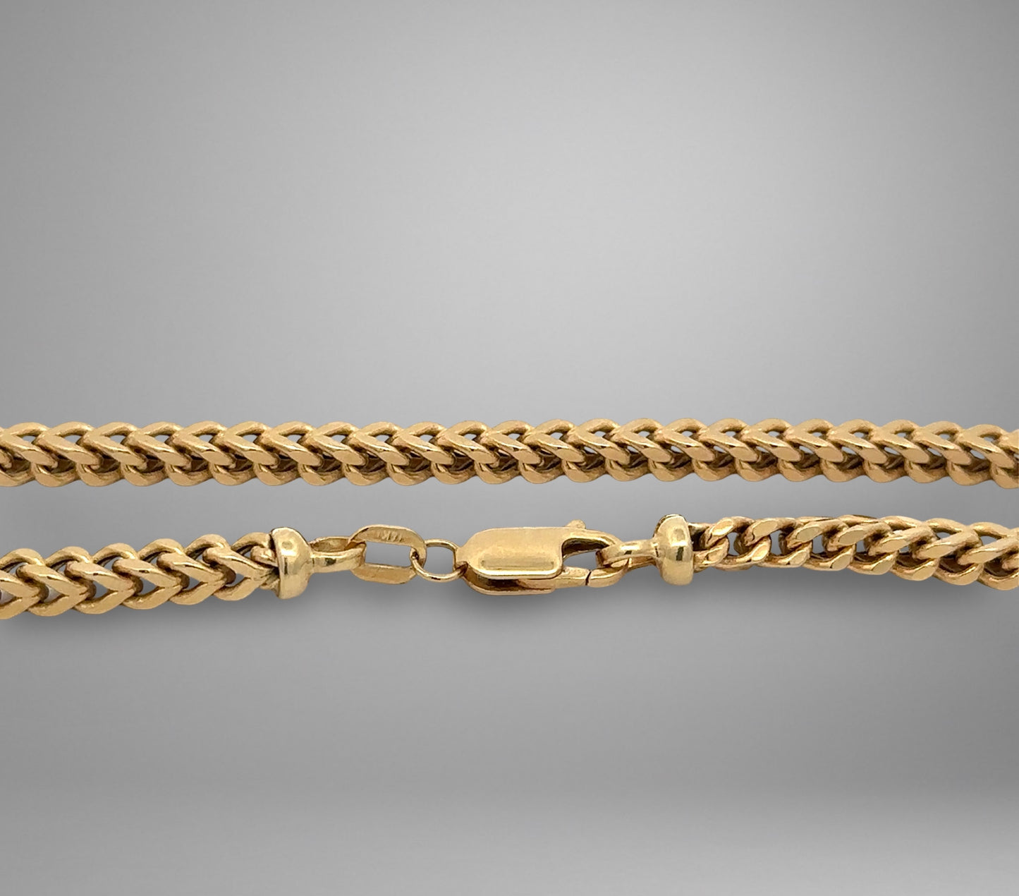 Gold chain necklace on a gray background