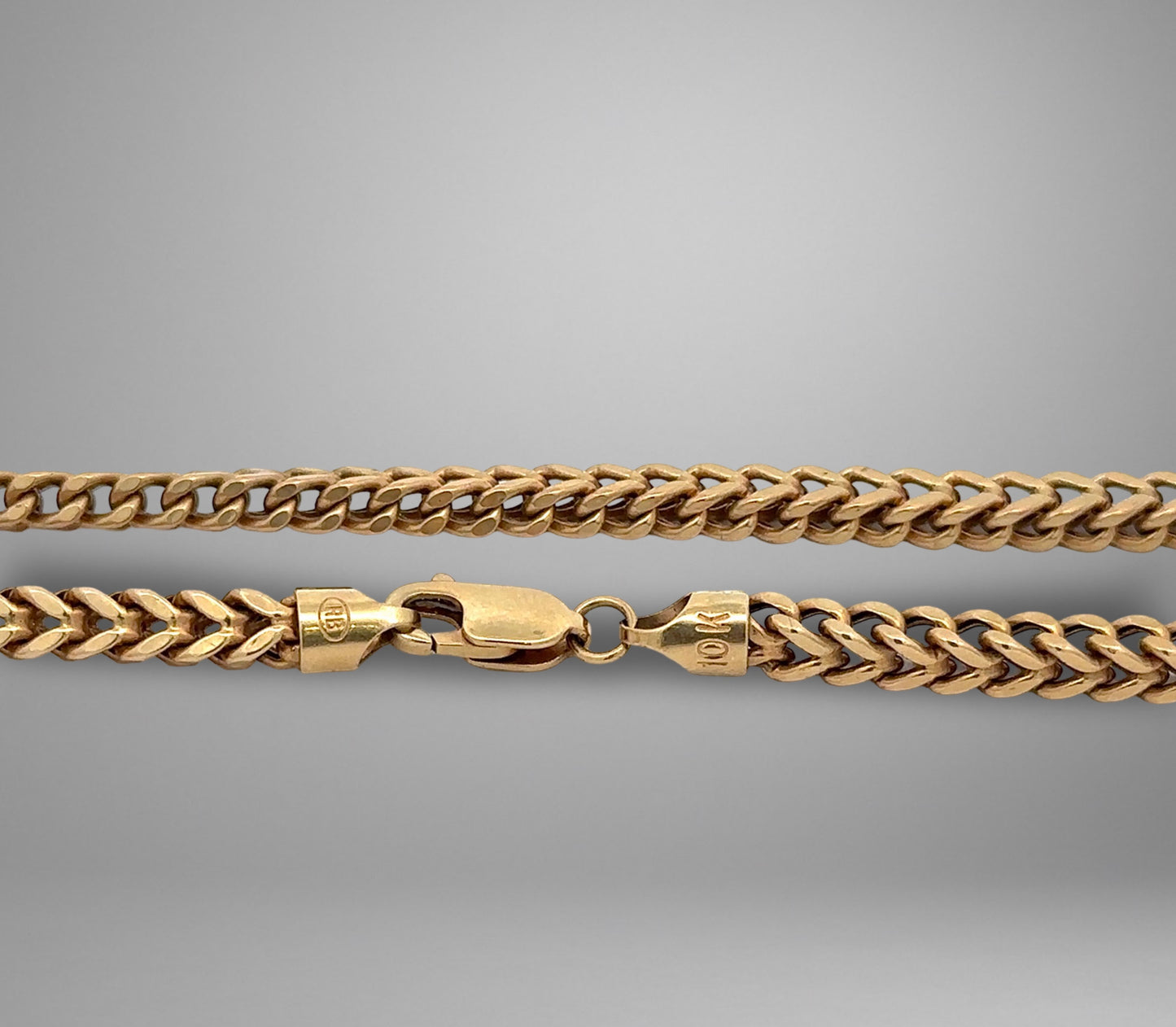 Gold chain necklace on a gray background