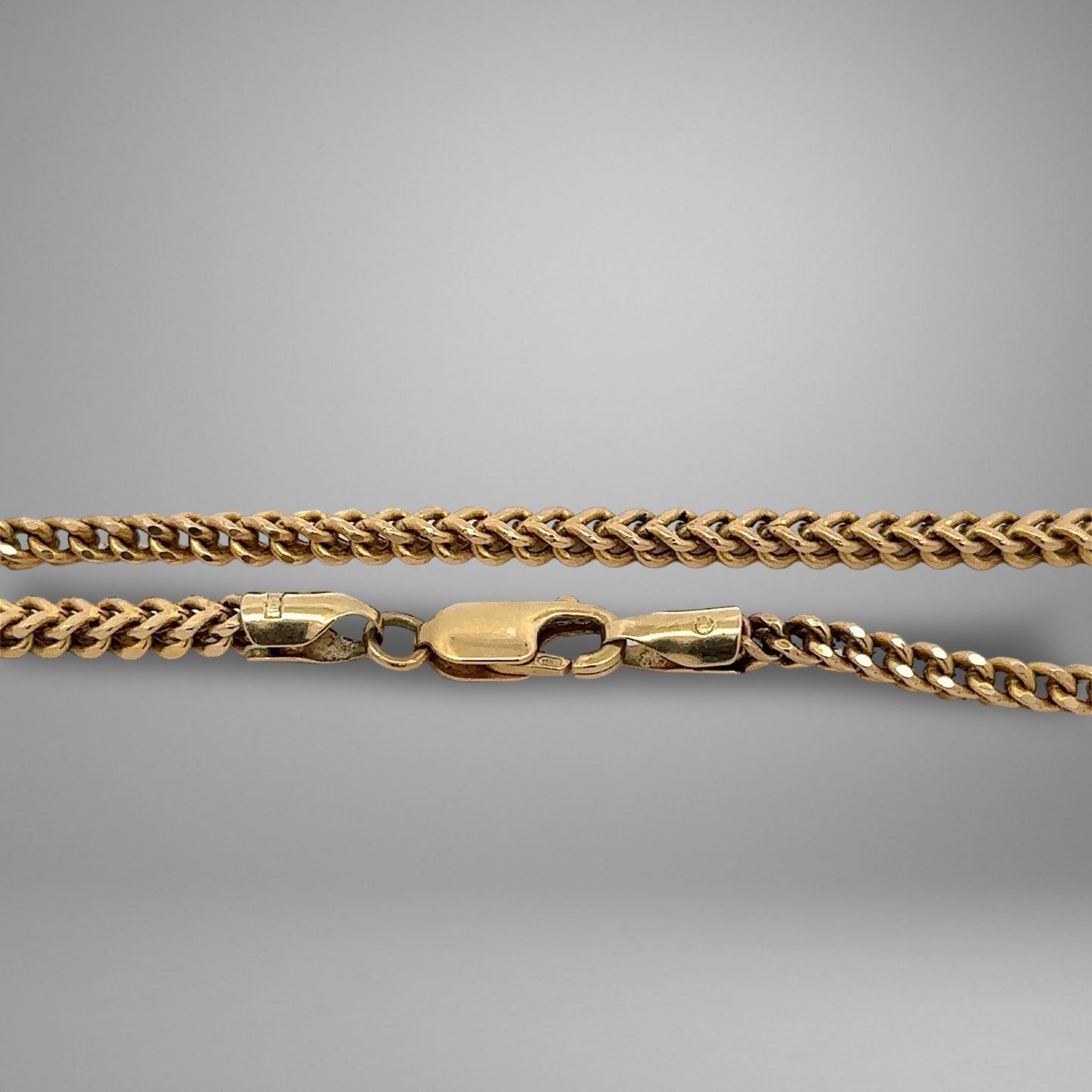 Gold chain necklace on a gray background