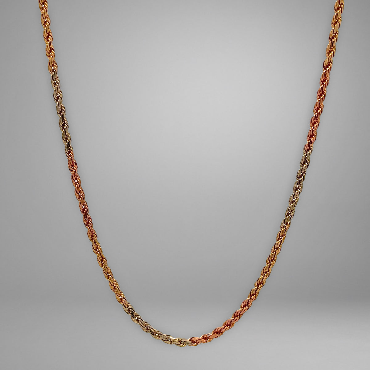 Yellow gold, rose gold, & white gold rope chain on grey background