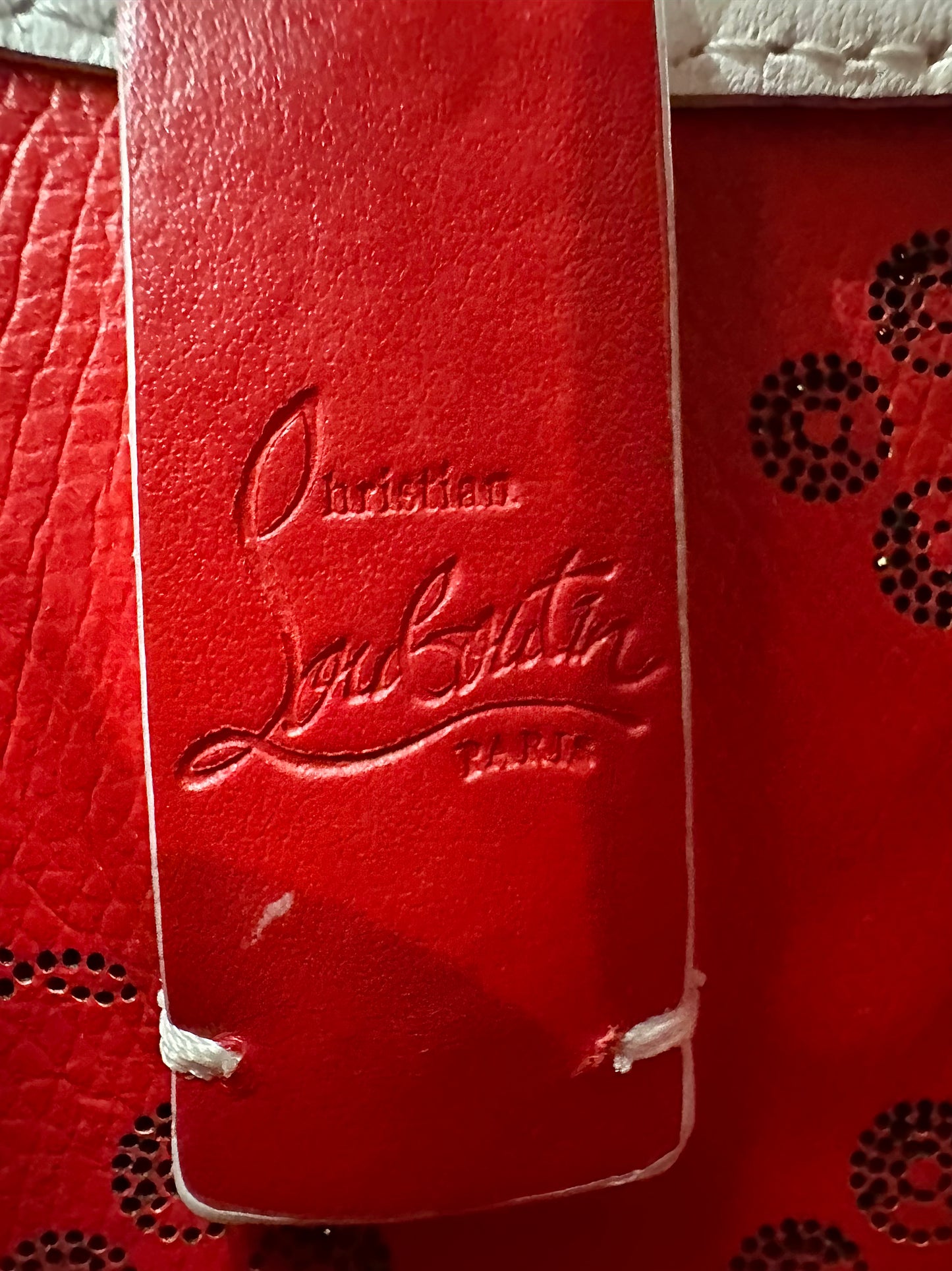 "Christian Louboutin Paris" inside purse. White scuff mark below signature