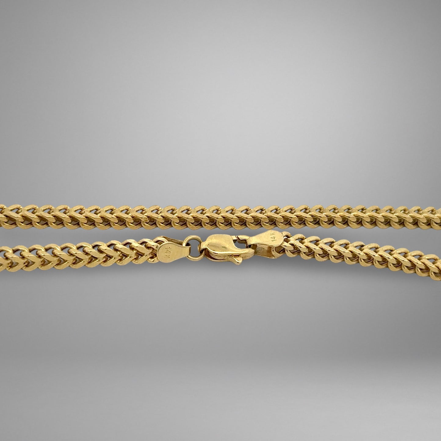 Gold chain necklace on a gray background
