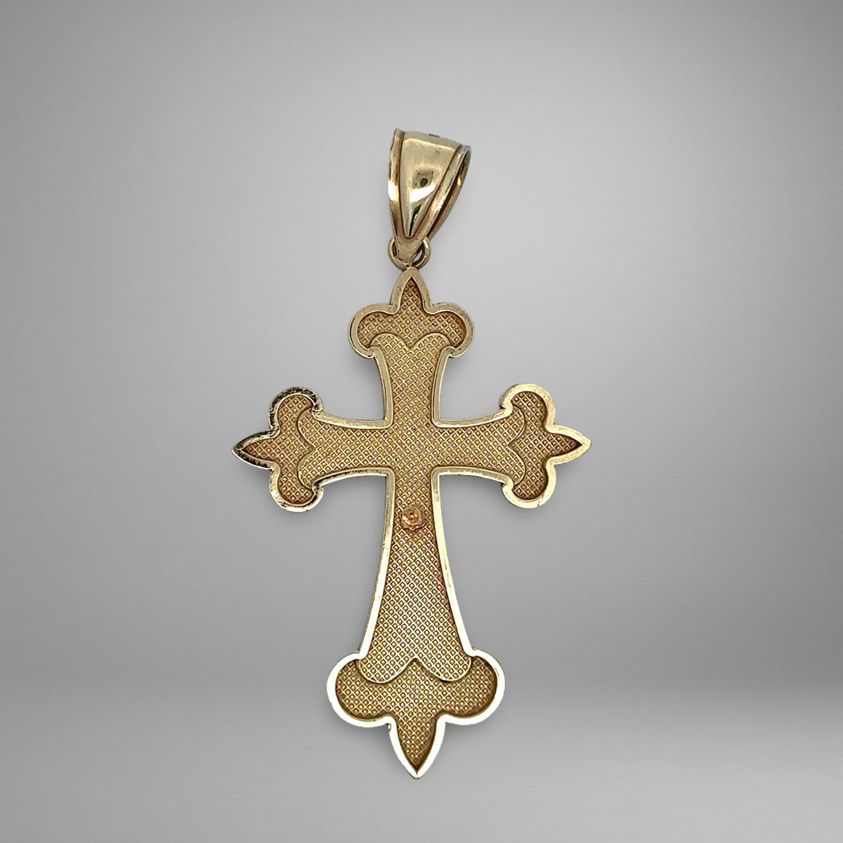 Gold cross pendant on a gray background
