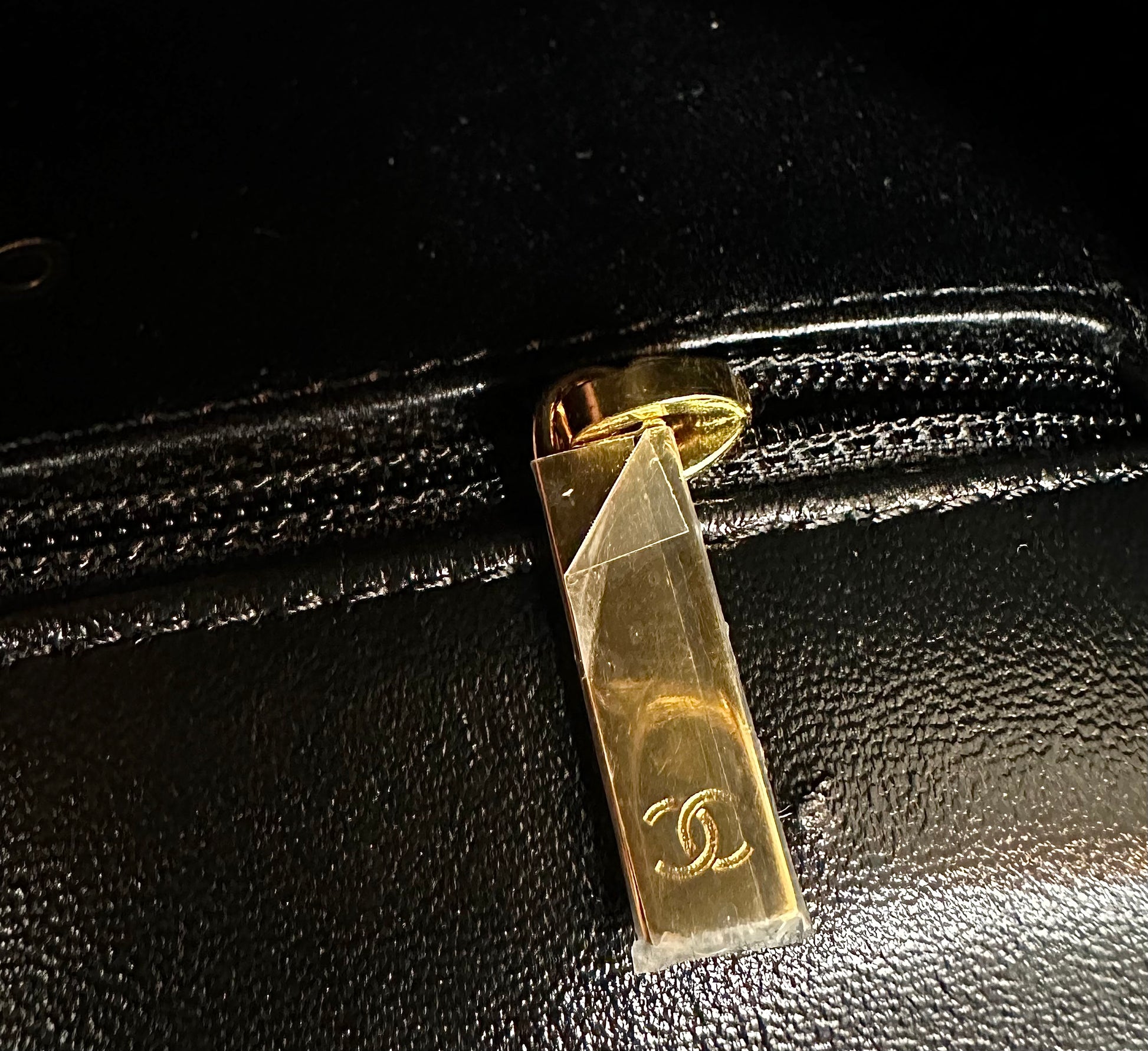 Close up of Chanel logo on gold interior zipper with plastic still on it