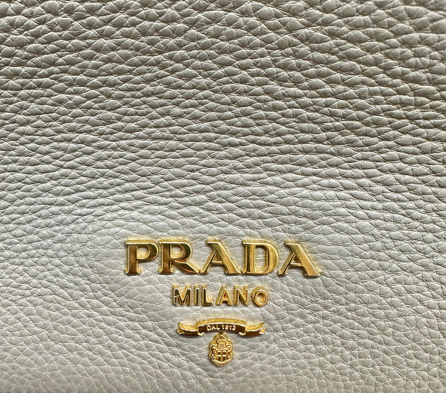 Close up of gold Prada logo on front of bag