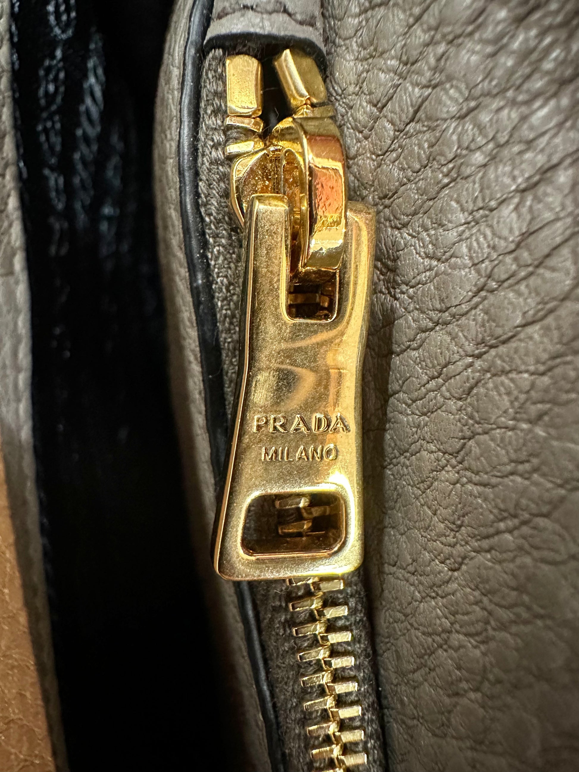 Close up of gold Prada zipper with scratches
