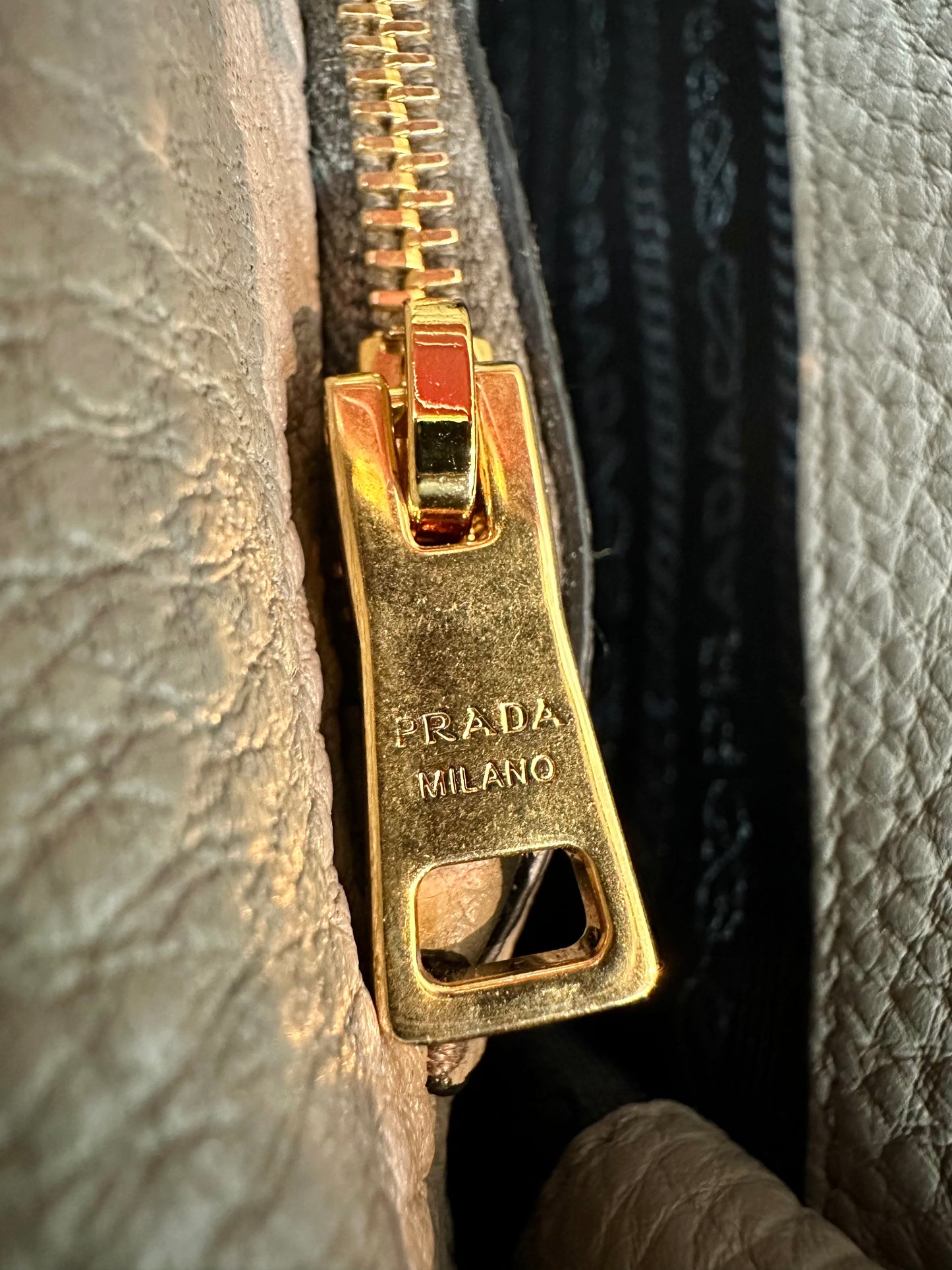 Close up of gold Prada zipper with scratches