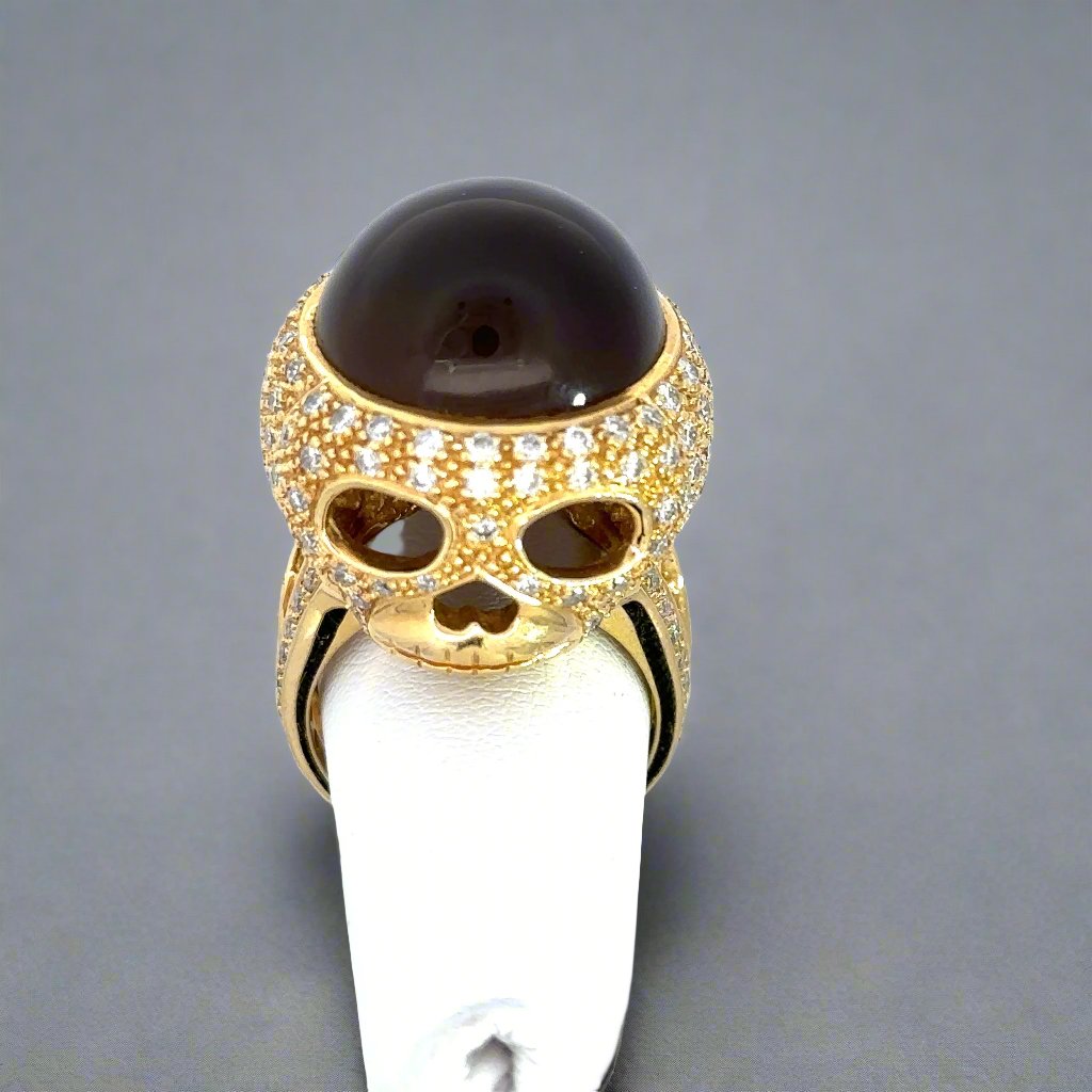 The top of the skull ring. You can see the brown cat's eye gemstone and the skull face. Small scratches on the band.
