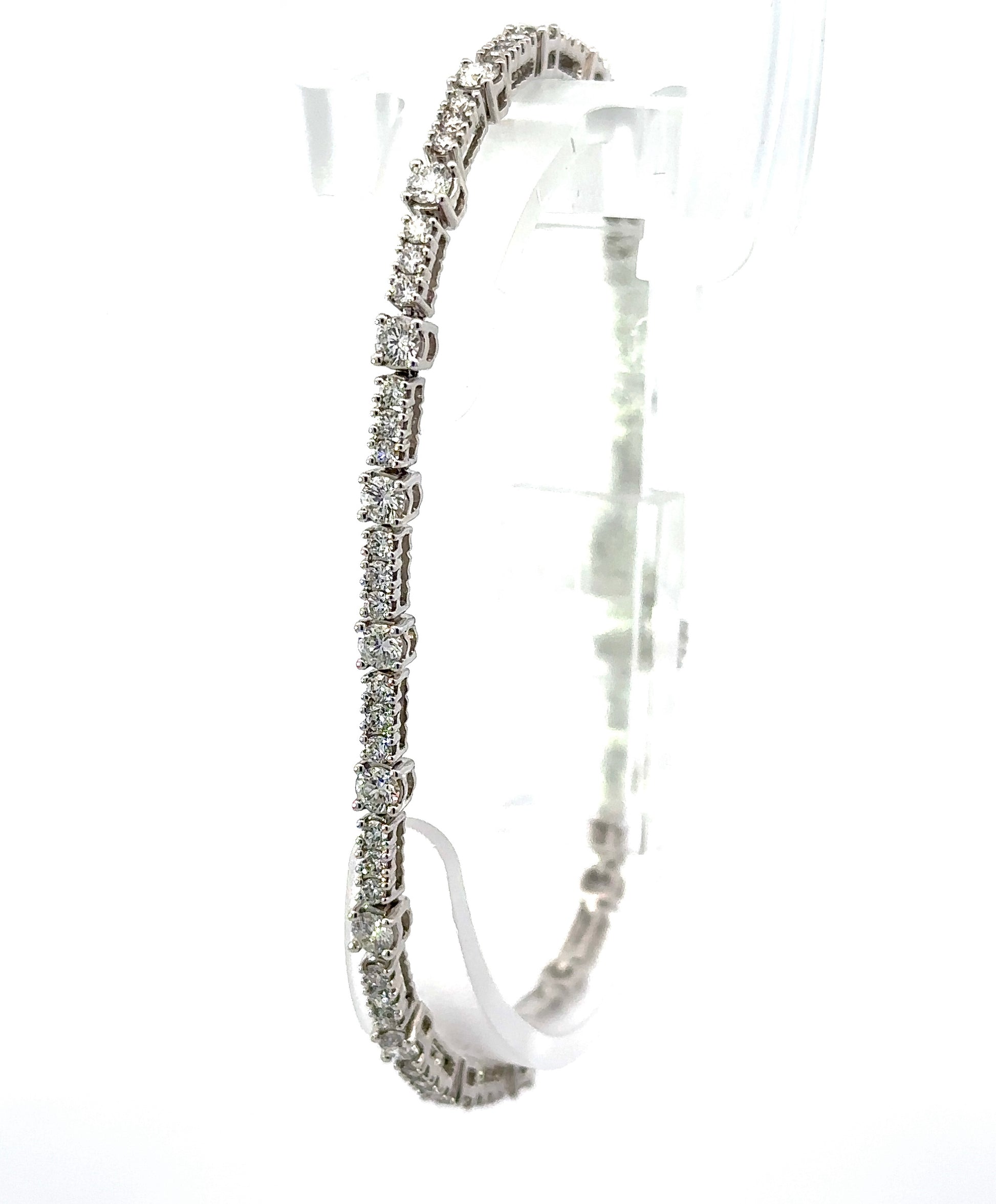 diagonal view of white gold tennis bracelet with alternating sizes of diamonds