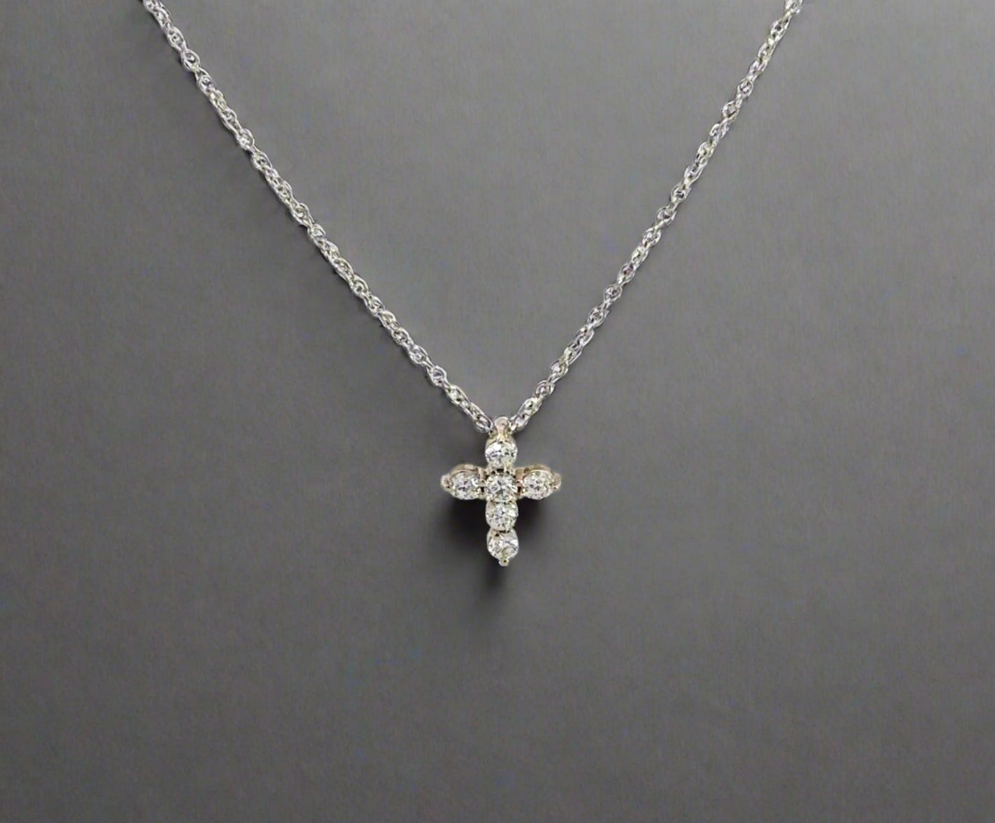 front of mini white gold diamond cross necklace with 6 small round diamonds