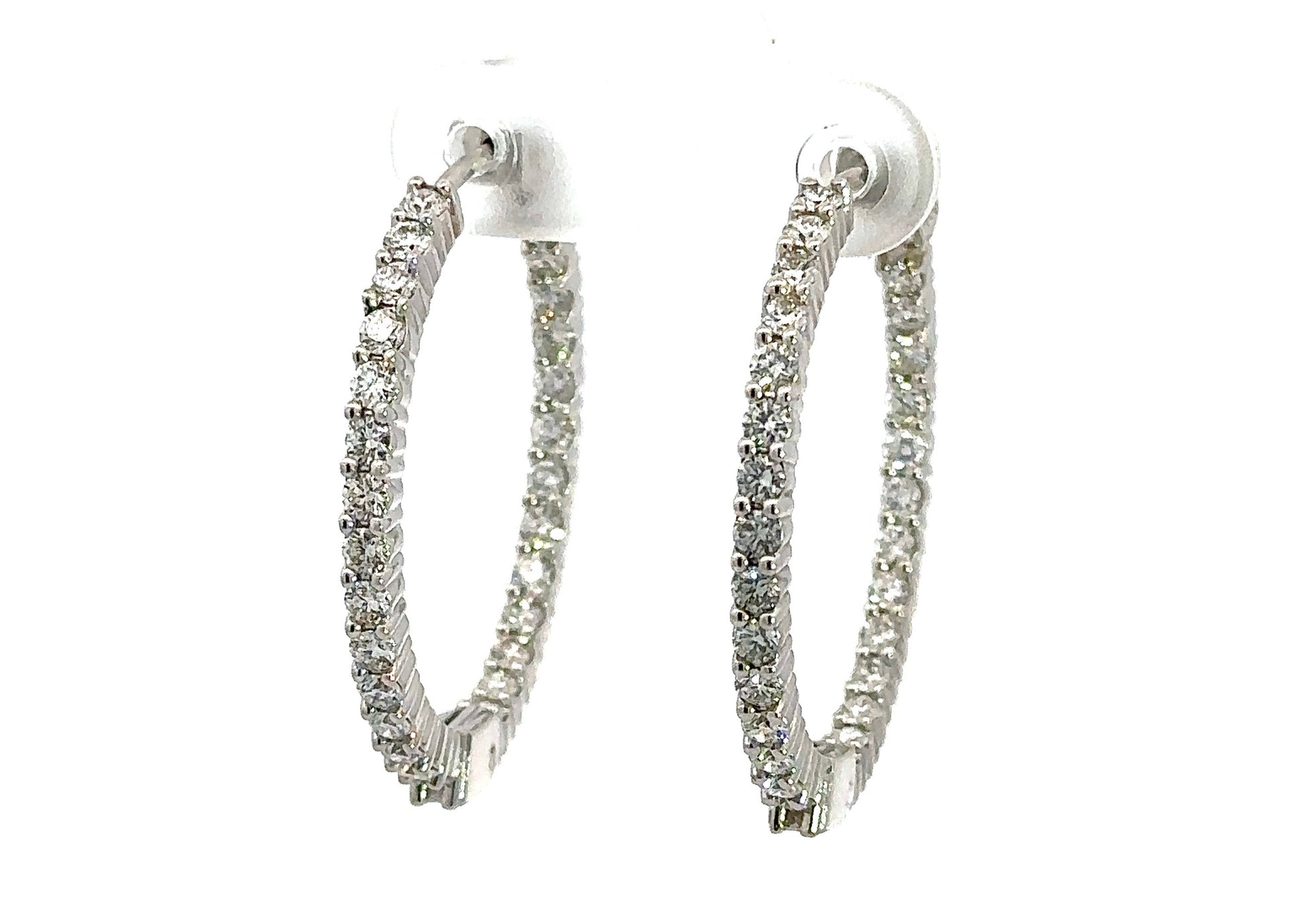 Diagonal view of white gold inside out diamond hoops with round diamonds on front and round diamonds on inside
