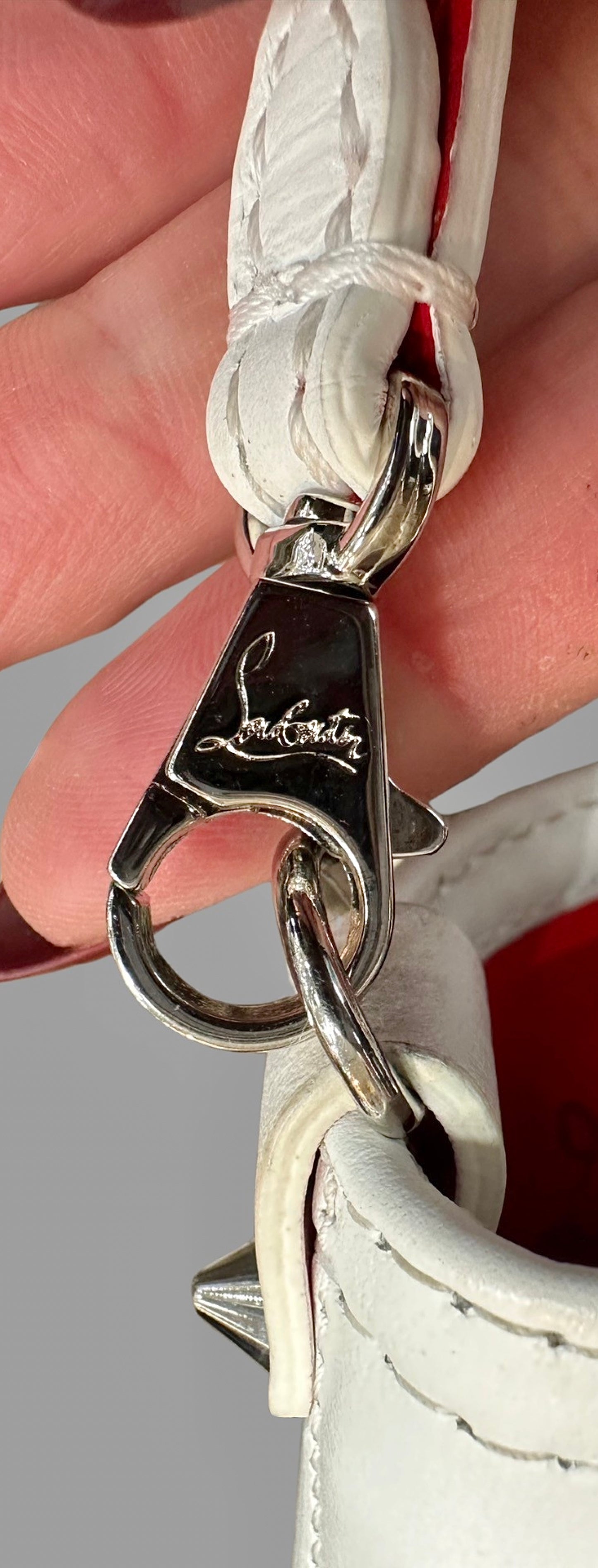 Close up of silver clasp on detachable strap with "Louboutin" signature