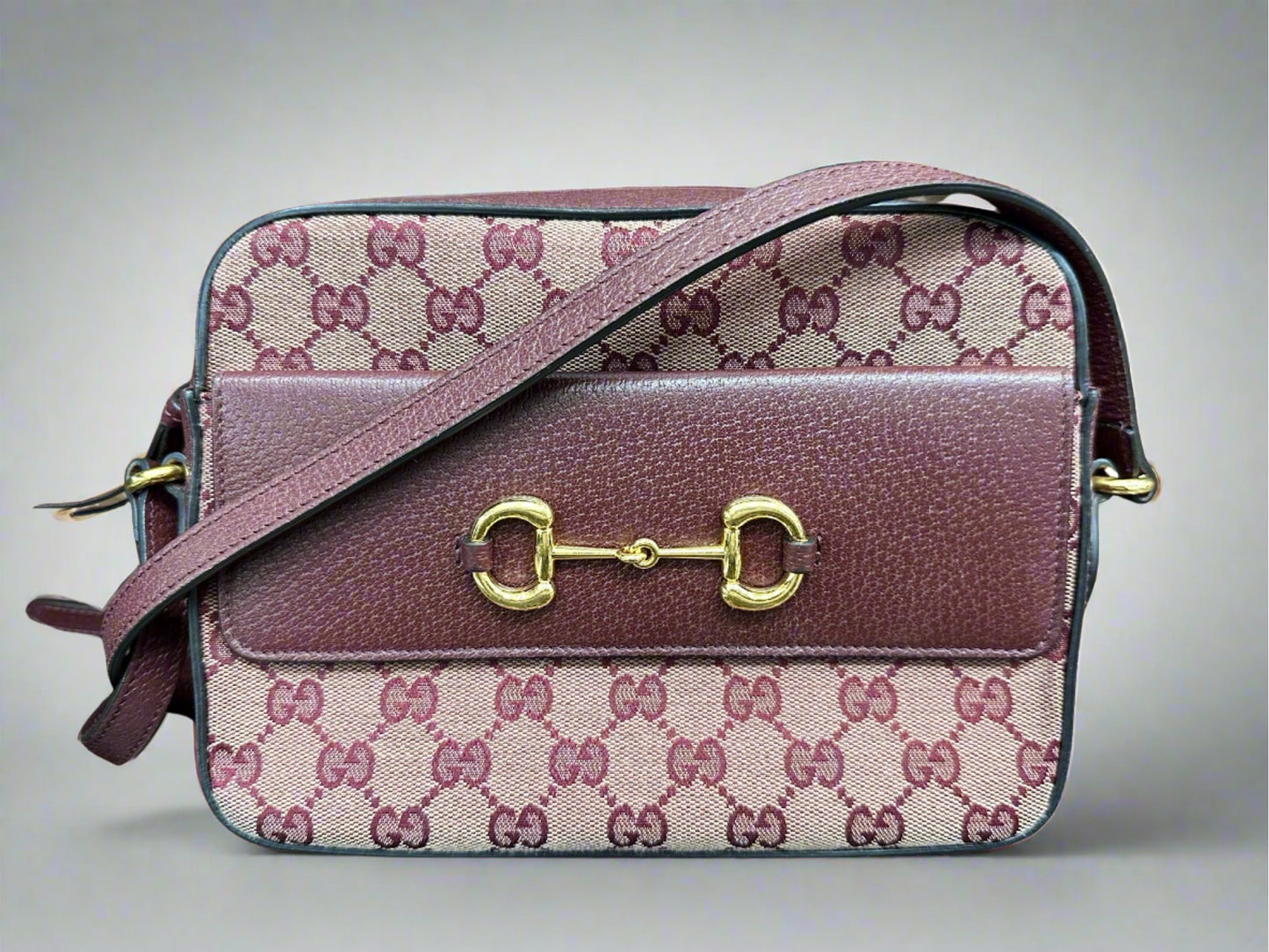 Front of burgundy Gucci bag with flap on the front and gold hardware