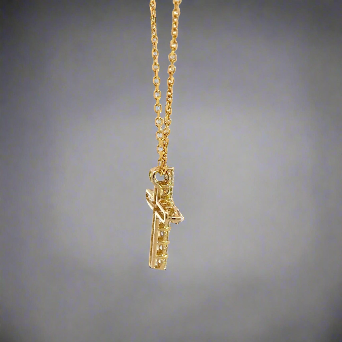 Side of yellow gold diamond cross necklace with open back on cross.