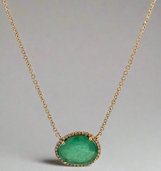 Hanging yellow gold necklace with a free-form emerald and small round diamonds around it