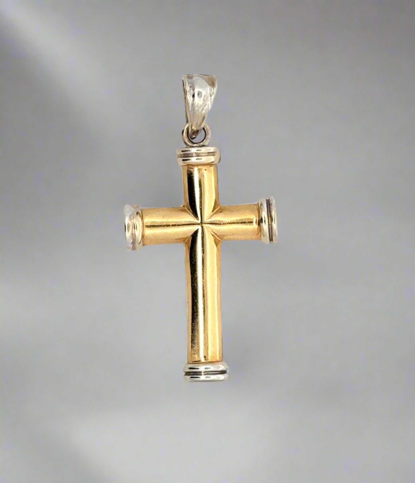 Front of yellow and white gold cross pendant with yellow gold cross and white gold border on top, bottom, and sides and white gold bail. Scratches on gold