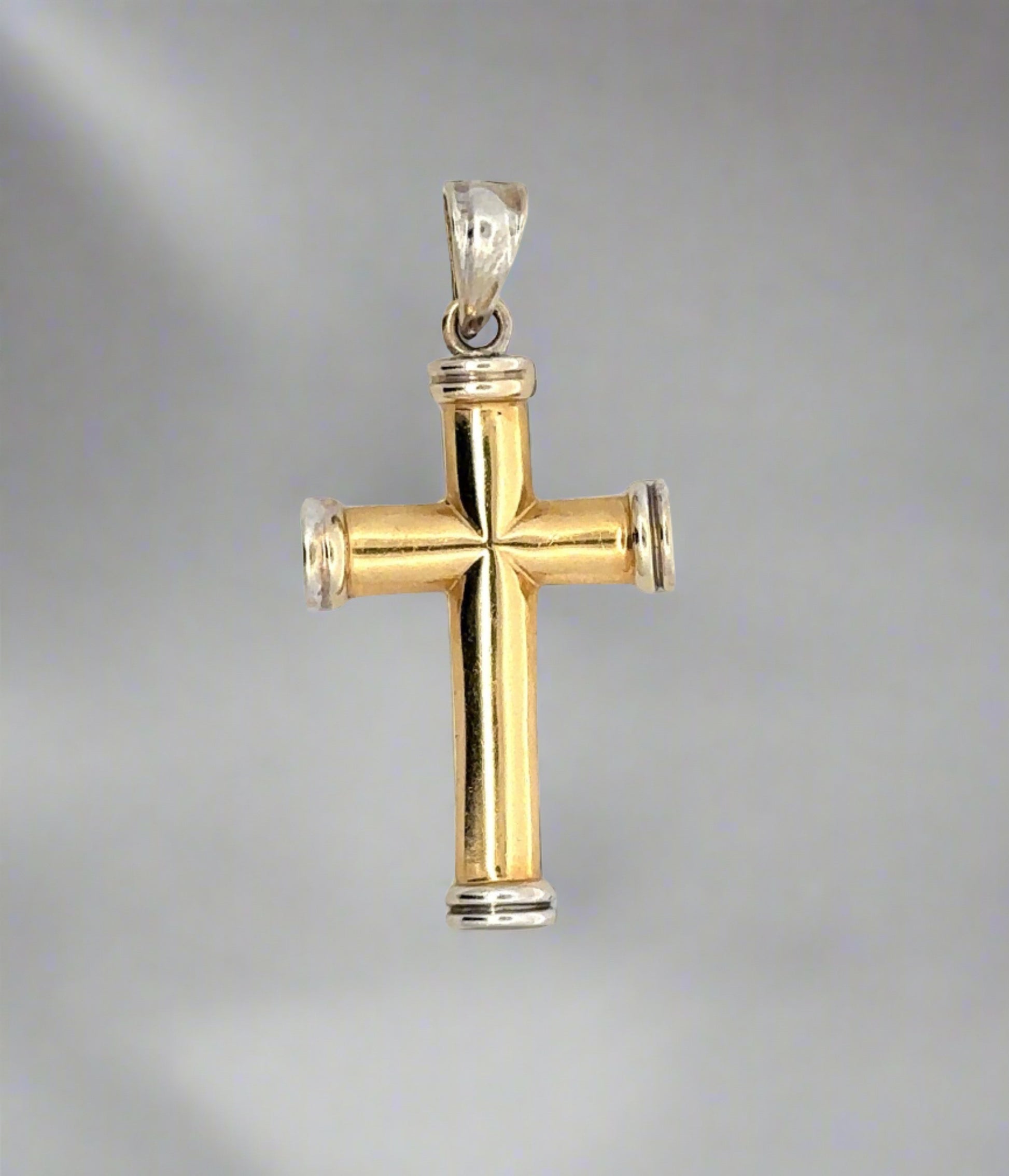 Front of yellow and white gold cross pendant with yellow gold cross and white gold border on top, bottom, and sides and white gold bail. Scratches on gold