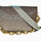 Front of taupe embossed monogram bag with 2 straps, 1 fabric strap with Louis Vuitton logo and 1 gold strap