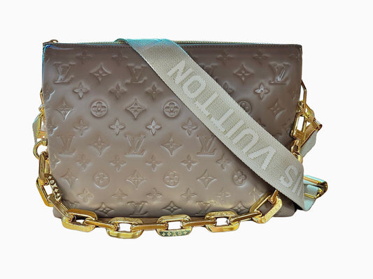 Front of taupe embossed monogram bag with 2 straps, 1 fabric strap with Louis Vuitton logo and 1 gold strap
