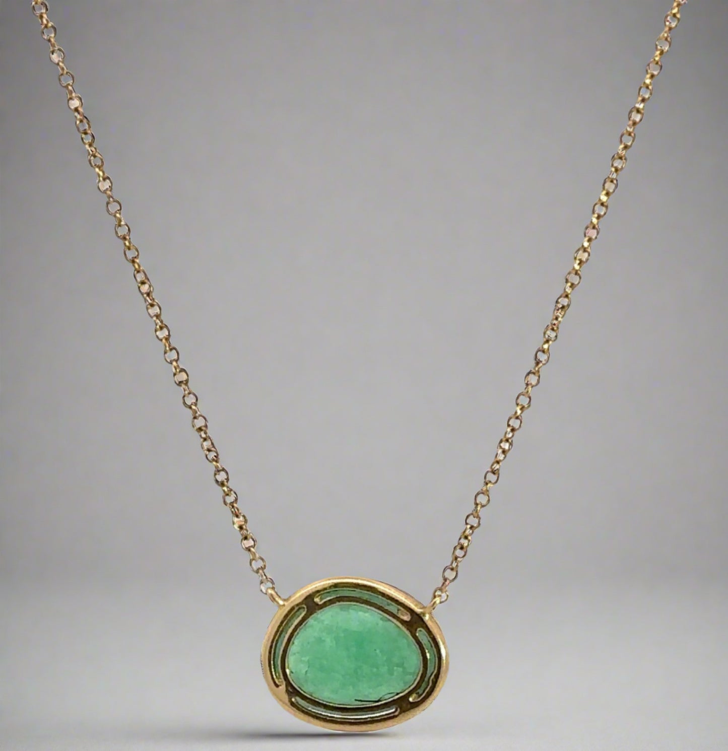 back of necklace with yellow gold surrounding free-form emerald