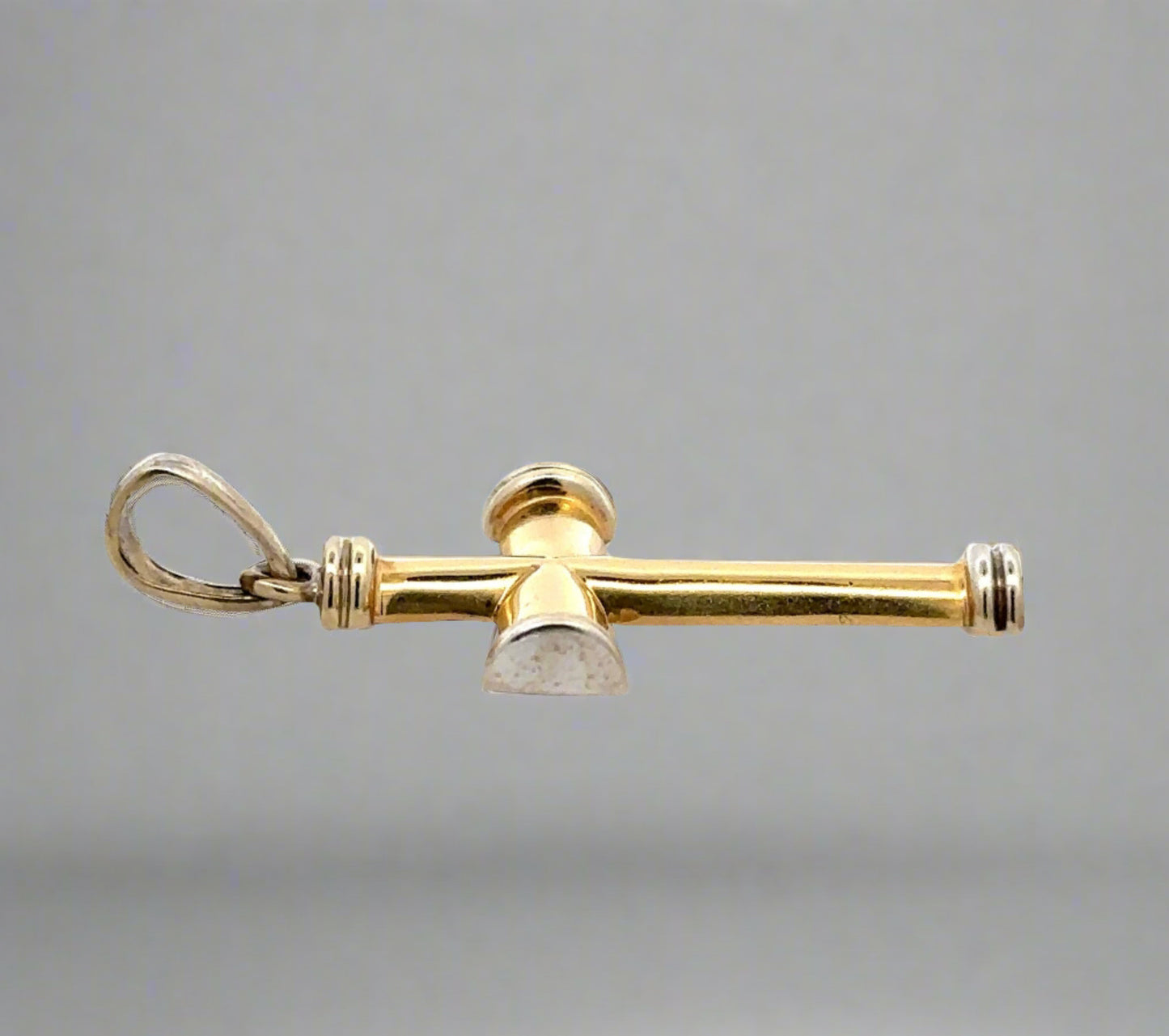 Side of yellow and white gold cross with scratches and marks on gold. Round bail